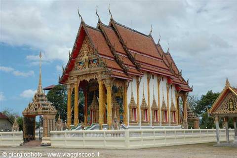 Thai Buddhist temple with ornate red roofs and golden details under cloudy sky
