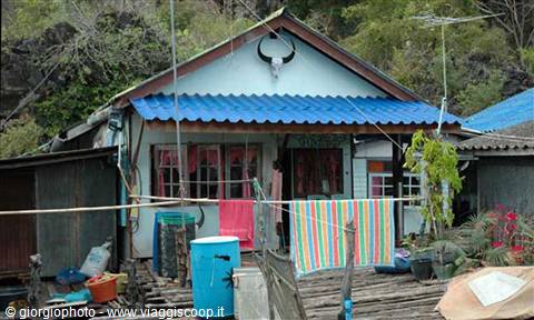Stilt house with blue roof, buffalo horns hanging and colorful laundry
