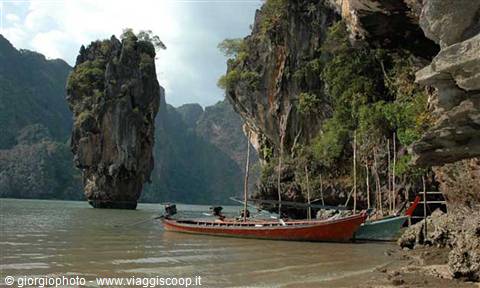Red longtail boat beached beneath the limestone cliffs of Khao Phing Kan