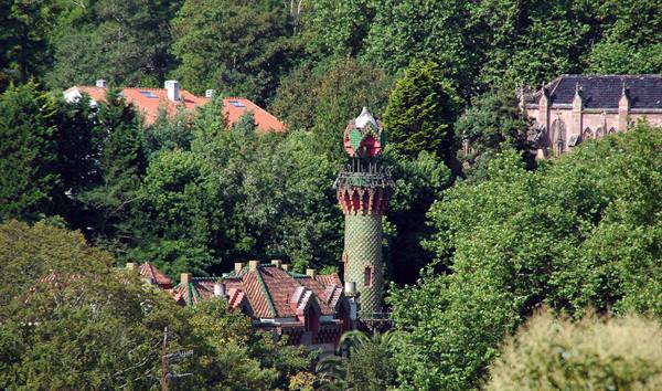 Tower decorated with green and red ceramics among trees, El Capricho by Gaudí