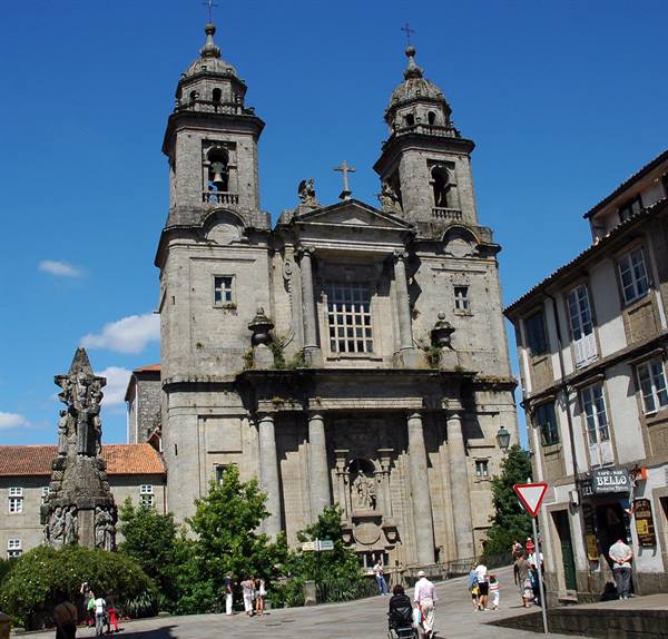 Baroque granite facade of San Francisco church in Santiago de Compostela, tourists in sunlight