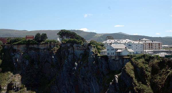 White houses and hotel on green cliffs, blue sky with light clouds