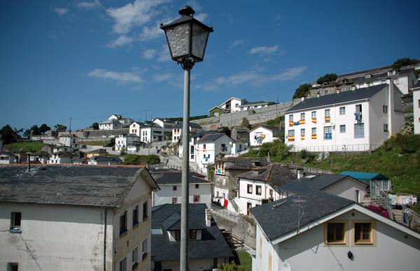 A street lamp in front of whitewashed houses on the hillside under blue sky