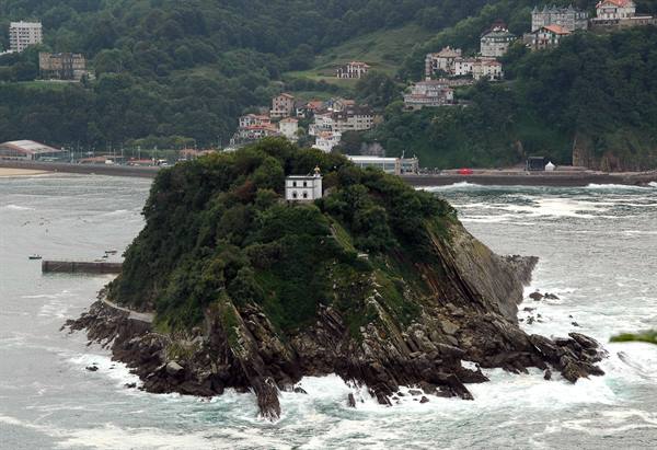 Santa Clara Island in San Sebastián, rocky cliffs, green trees, waves crashing