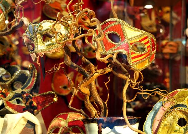 Colorful Venetian carnival masks hanging on intertwined branches in a shop