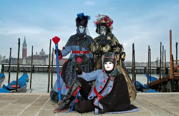 Three costumed masks at Venice carnival, San Giorgio Maggiore in the background