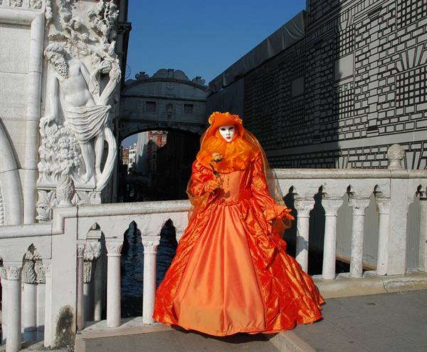 Carnival mask in orange gown by the Bridge of Sighs, Venice