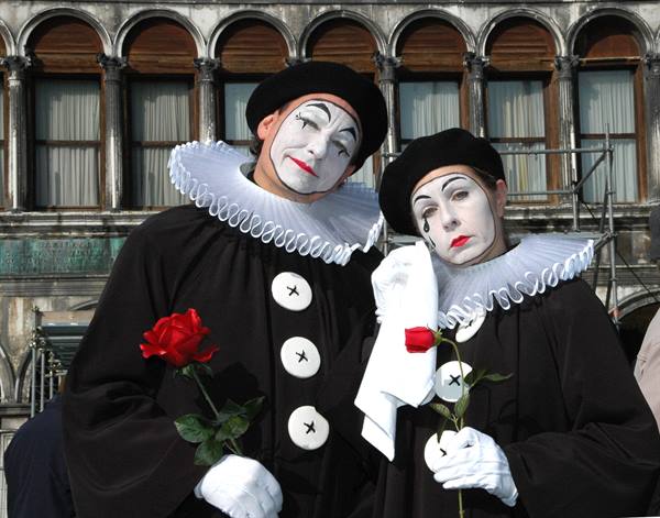 Two Pierrot mimes holding red roses in St Mark's Square, Venice