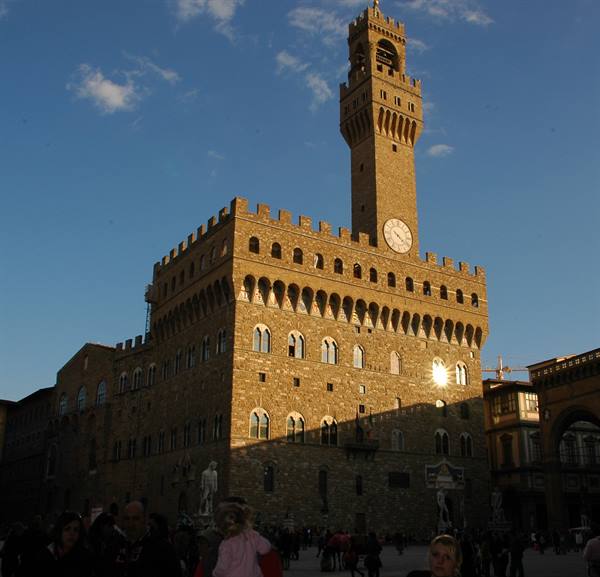 Tourists in Piazza della Signoria before Palazzo Vecchio, Florence, sandstone glowing in sunlight