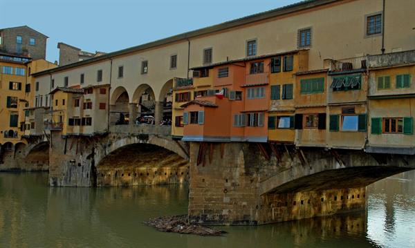 Ponte Vecchio in Florence, colorful houses on stone piers reflected in the Arno