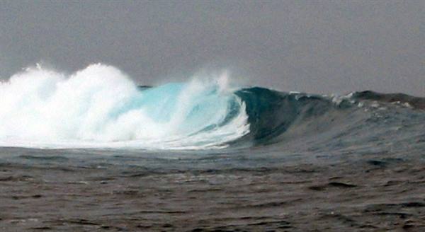 Turquoise wave breaking with white foam in the open ocean