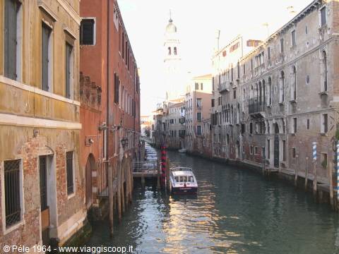 Vaporetto on a Venice canal between old buildings, bell tower behind
