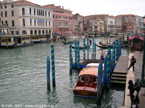 Water taxi moored on the Grand Canal, colorful palaces and striped blue poles