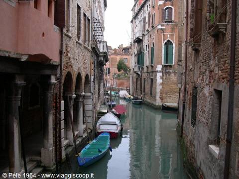 Boats moored along a narrow canal between brick houses, Venice
