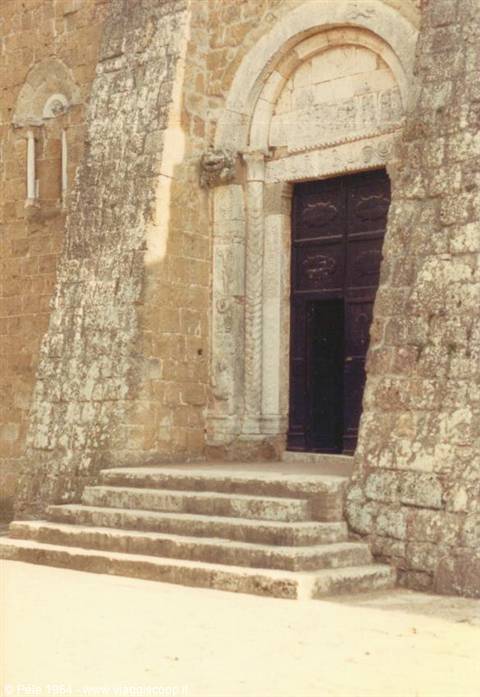 Romanesque stone portal with steps, mossy walls, daylight