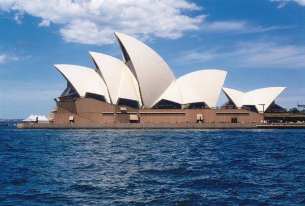 White sails of Sydney Opera House rising above blue harbour water