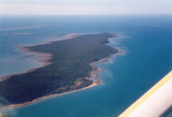 Green island surrounded by turquoise sea, photographed from an airplane by day