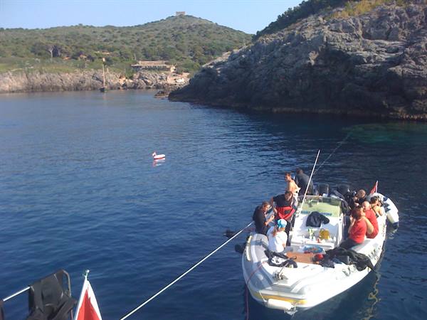 White inflatable dive boat with scuba gear in a rocky cove