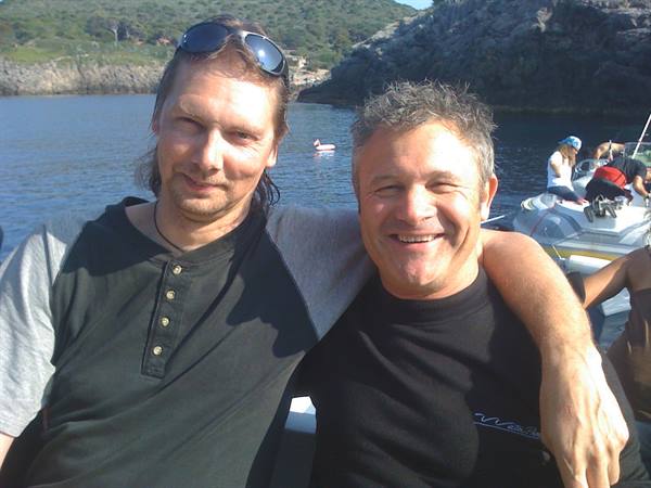 Two men embracing on a boat in a rocky cove