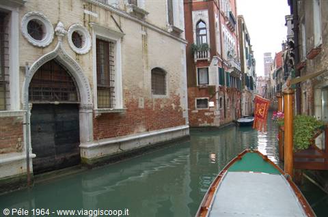 Boat bow gliding past old Gothic palaces along a narrow Venice canal