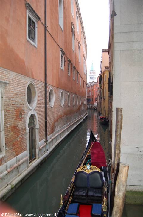 Gondola moored along a narrow Venice canal, St Mark's bell tower in the background