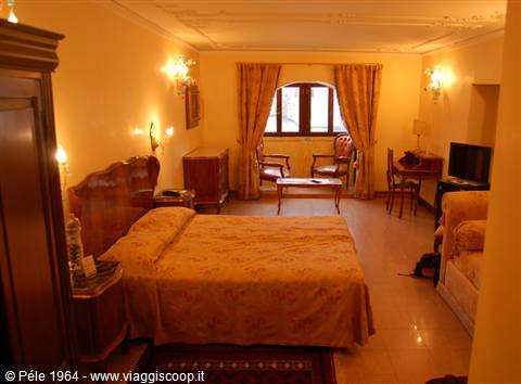 Hotel room with double bed, armchairs by the window and warm lamplight