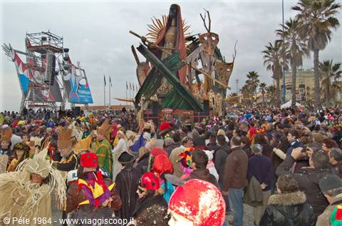 Viareggio Carnival: crowd among palm trees around the giant paper float