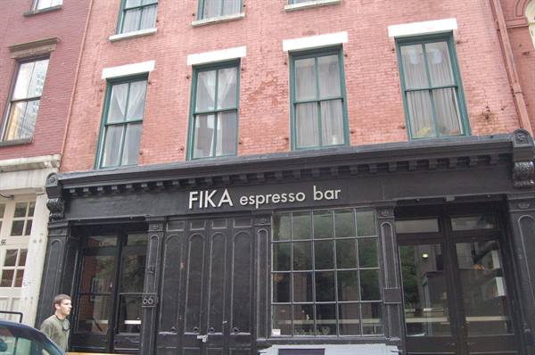 Man walks past FIKA espresso bar, red brick building in New York
