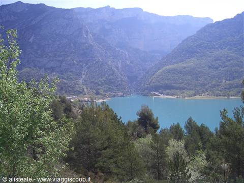 Turquoise lake nestled among rocky mountains, pines and trees in the foreground