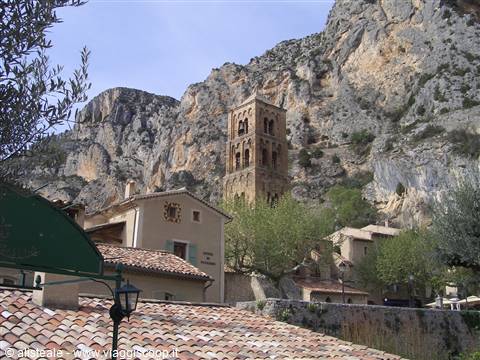 Romanesque stone bell tower beneath the limestone cliffs of Moustiers-Sainte-Marie
