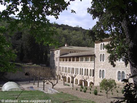 Stone monastery with arched windows among trees, sunny courtyard with bare trees