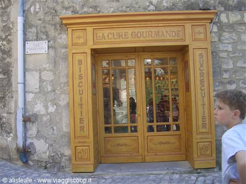 Boy standing in front of La Cure Gourmande's yellow wooden candy shop